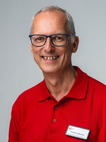 Thomas Gebauer im roten Oberteil mit Namensschildchen 